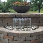 An outdoor water feature with potted plants and a fountain.