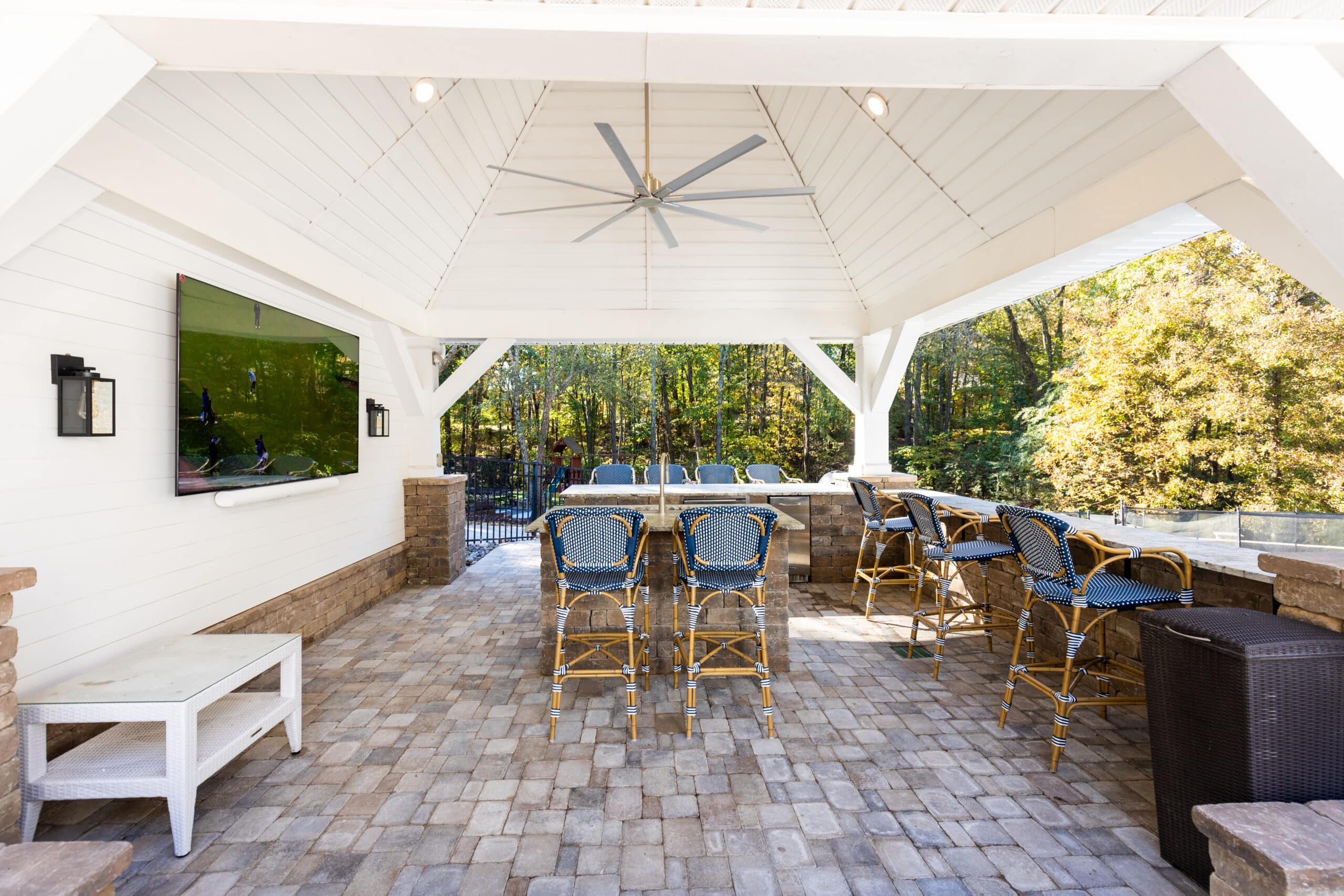 A brick patio with a grill and bar stools.