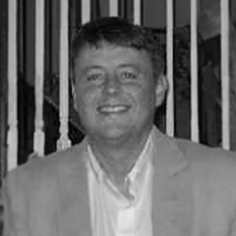 A black and white photo of a man smiling.